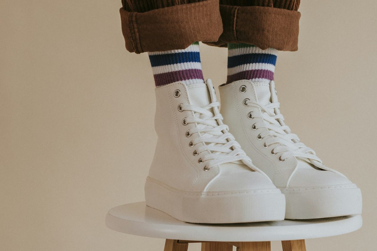 man in white high top shoes standing on chair -